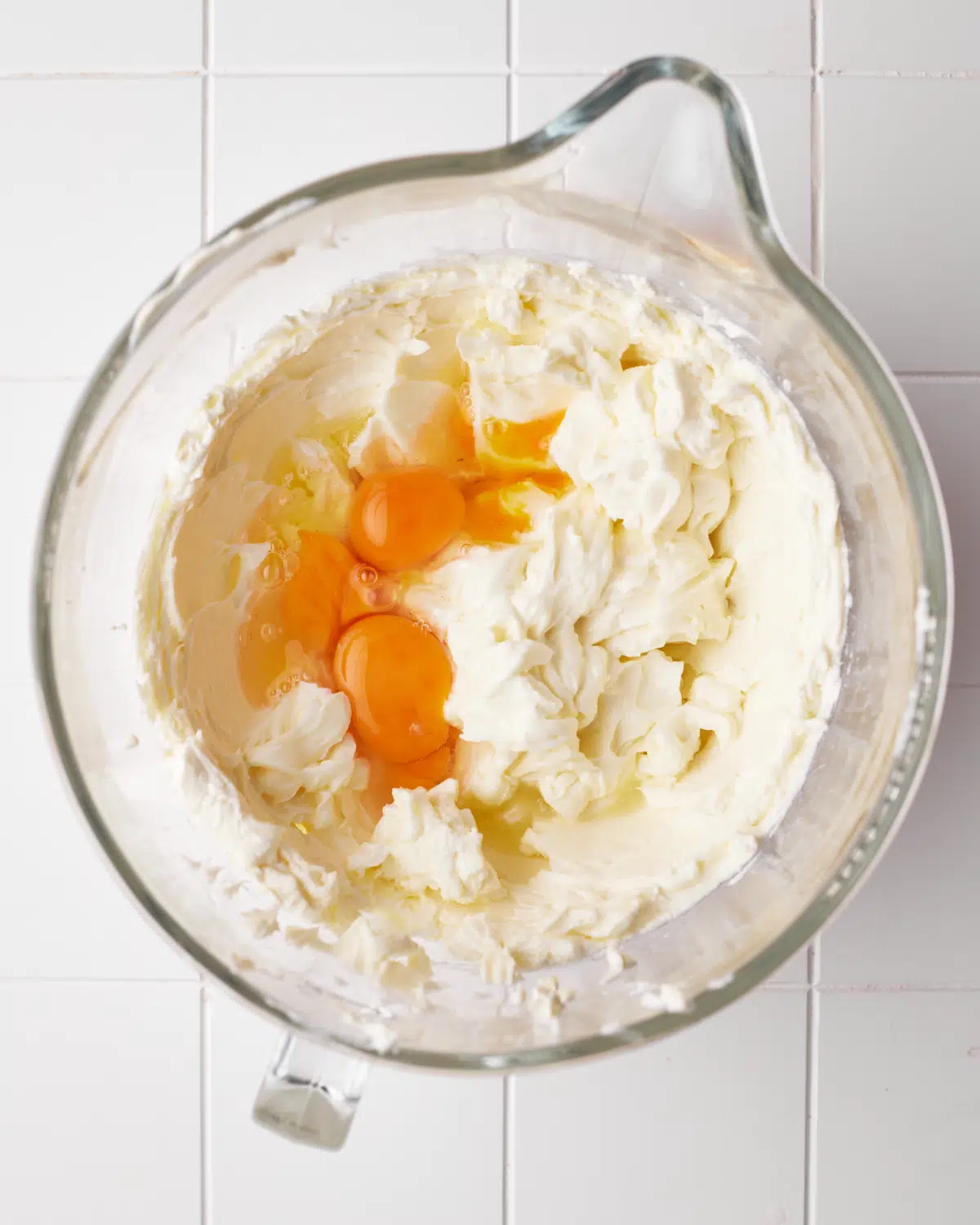 Eggs being added to cheesecake batter. 