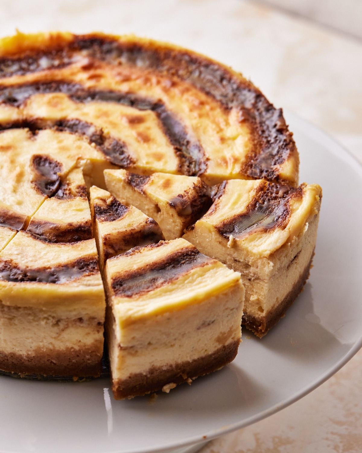 slices being taken out of a cinnamon roll cheesecake.