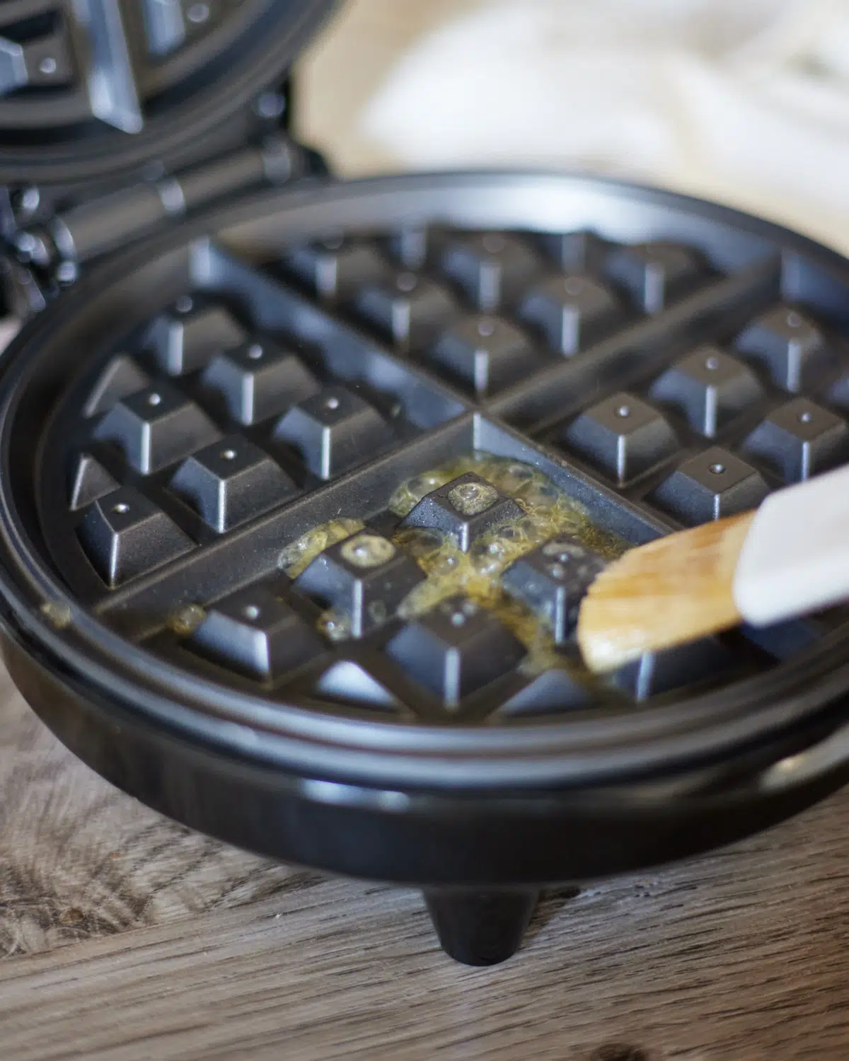 butter being brushed onto a hot waffle iron. 