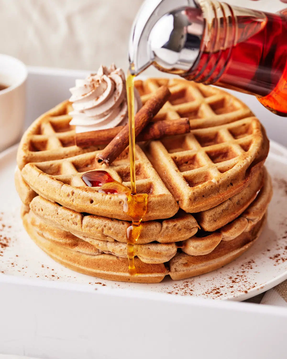 close up of maple syrup being poured on waffles. 