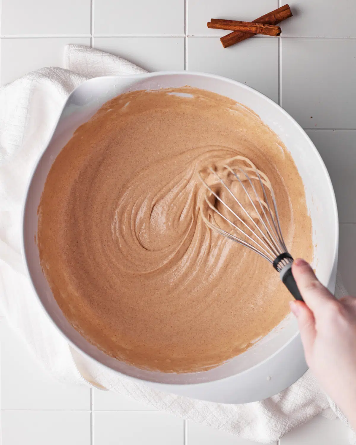 cinnamon waffle batter being whisked together in a large bowl.