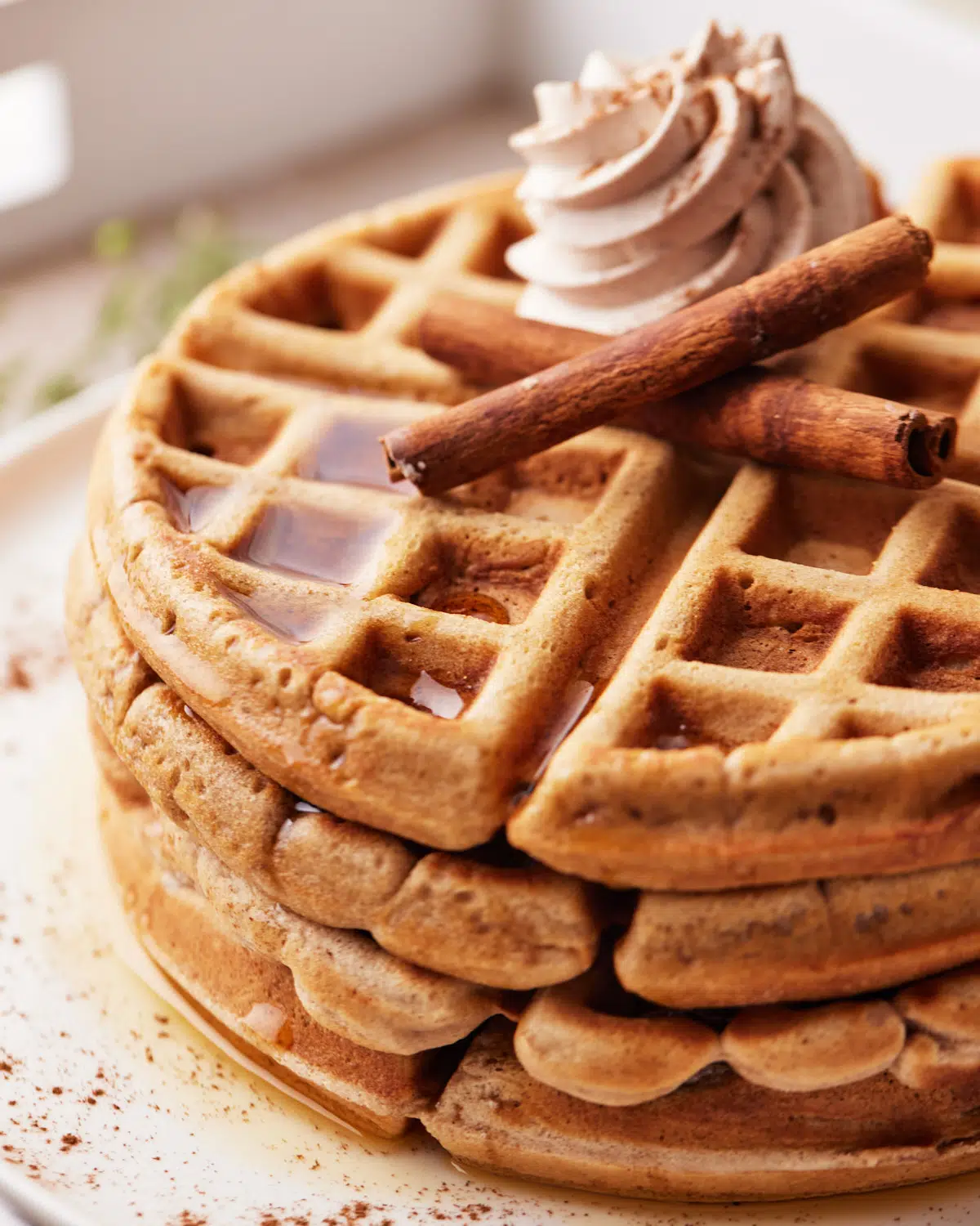 cinnamon whipped cream and maple syrup on top of cinnamon waffles.