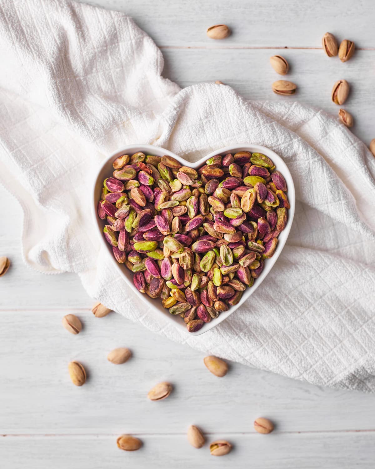 shelled pistachios in a heart shaped bowl. 