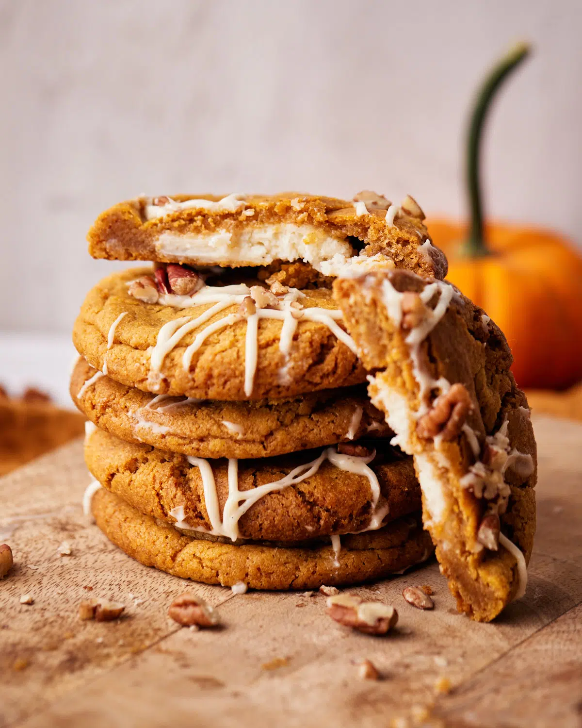 stack of pumpkin cheesecake cookies with cream cheese filling showing. 