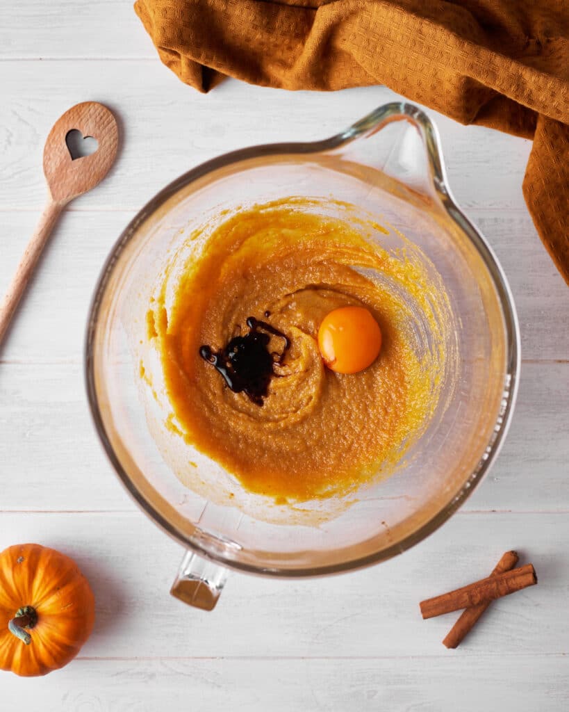 process shot of making pumpkin cheesecake cookies, adding egg yolk and vanilla into the cookie dough.