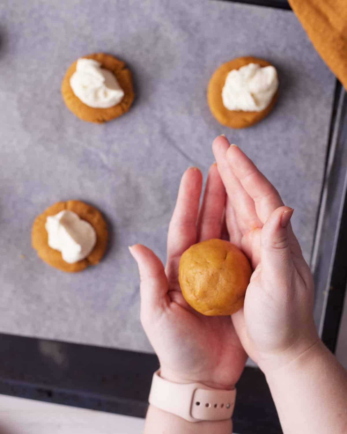 rolling pumpkin cheesecake cookies into a ball.