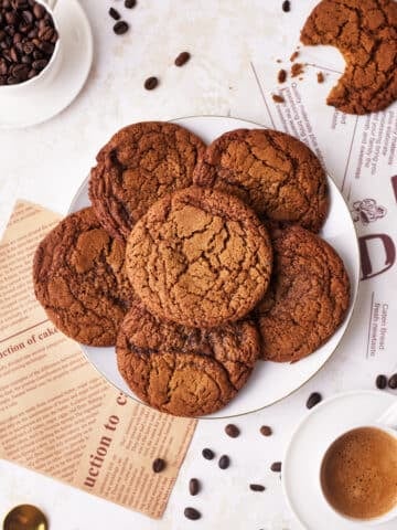 coffee cookies in a pile on a plate, surrounded by coffee beans and espresso.