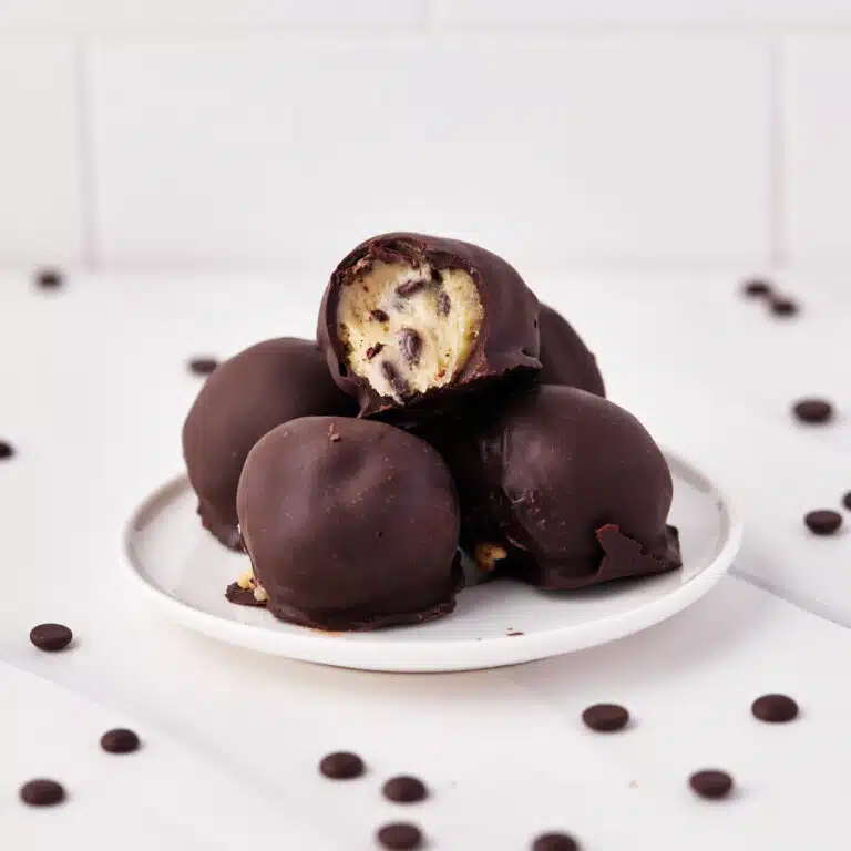 chocolate covered cookie dough bites on a small plate, surrounded by chocolate chips.