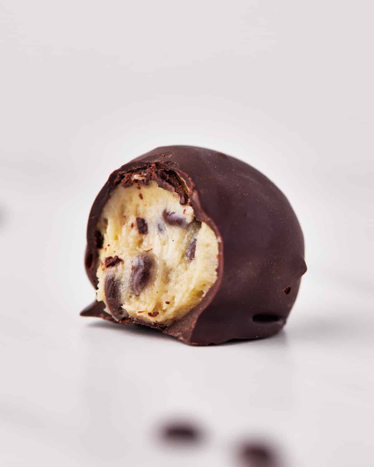 single chocolate covered cookie dough bite, with a bite taken out.