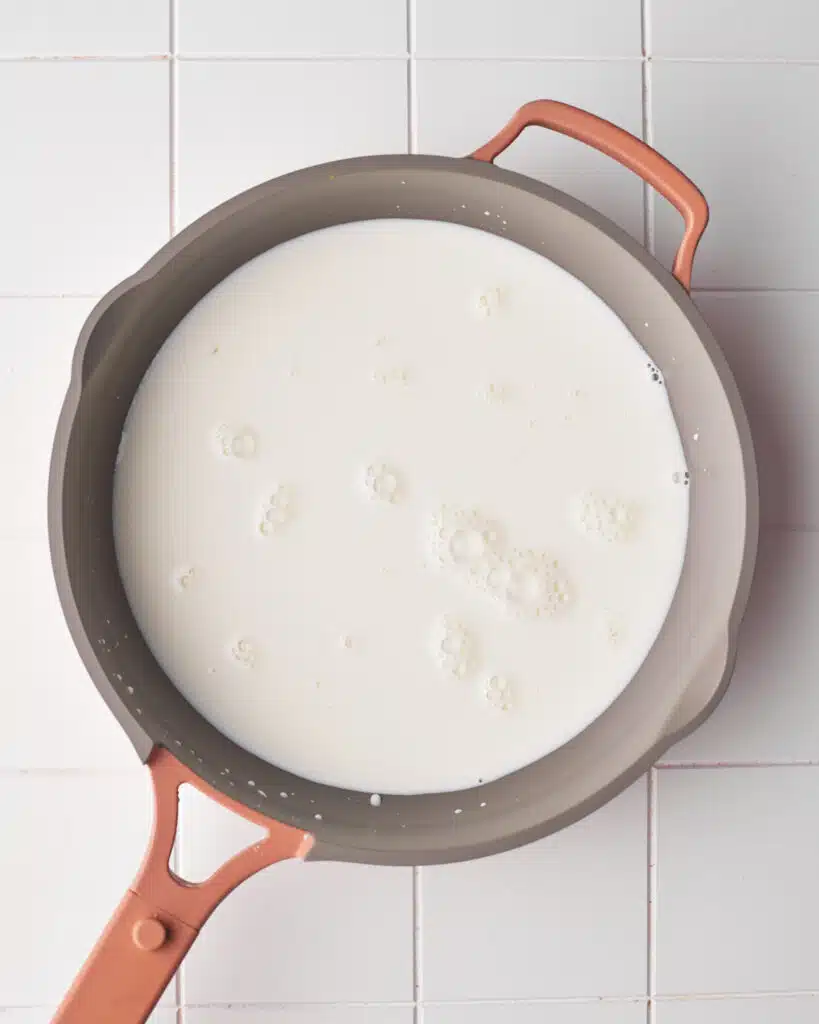 Milk being warmed in a pan for poaching meringues to make floating island dessert.