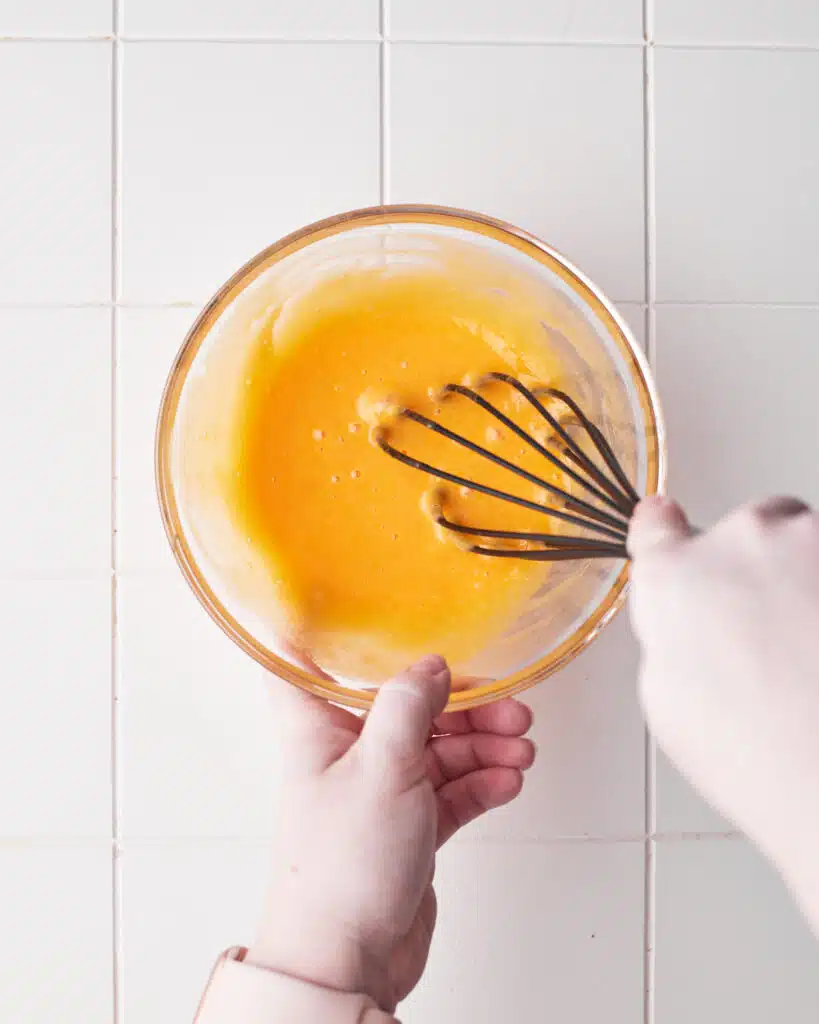 whisking egg yolks and sugar together to make floating island desserts.
