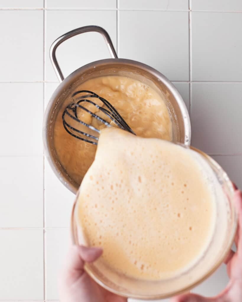 pouring custard into saucepan to make floating islands.
