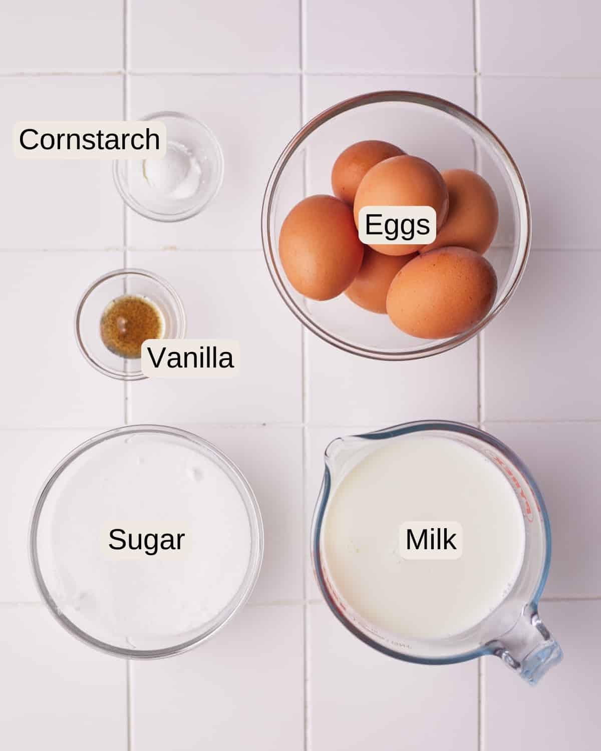 Ingredients to make floating island dessert including cornstarch, eggs, vanilla, sugar, and milk.