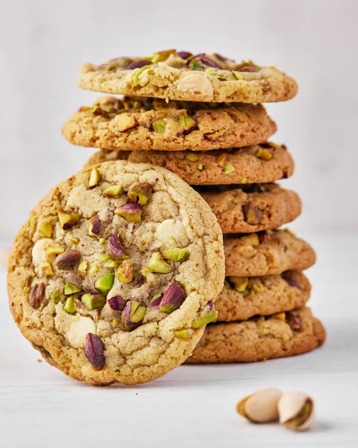 stack of pistachio cookies with one leaning on the side.