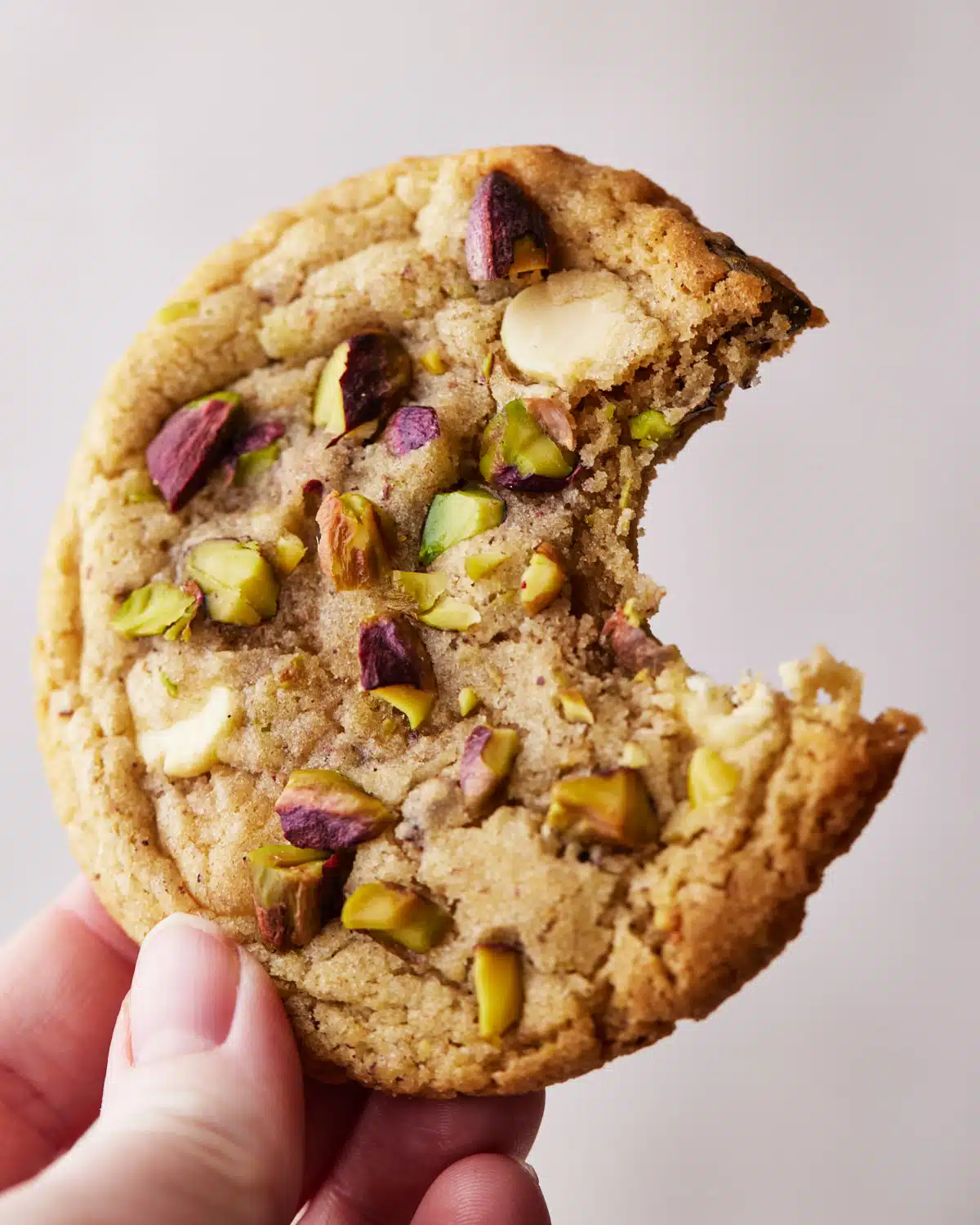close up of a pistachio cookie with a bite taken out of it.