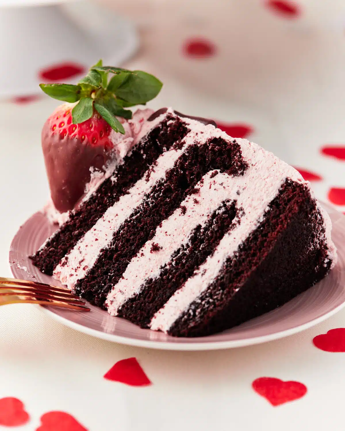 slice of chocolate strawberry cake with pink strawberry frosting inside.