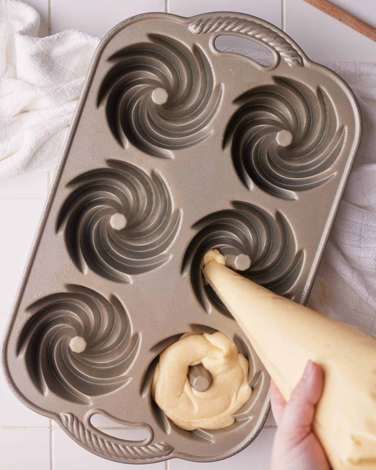 piping cake batter into a mini bundt cake mold.