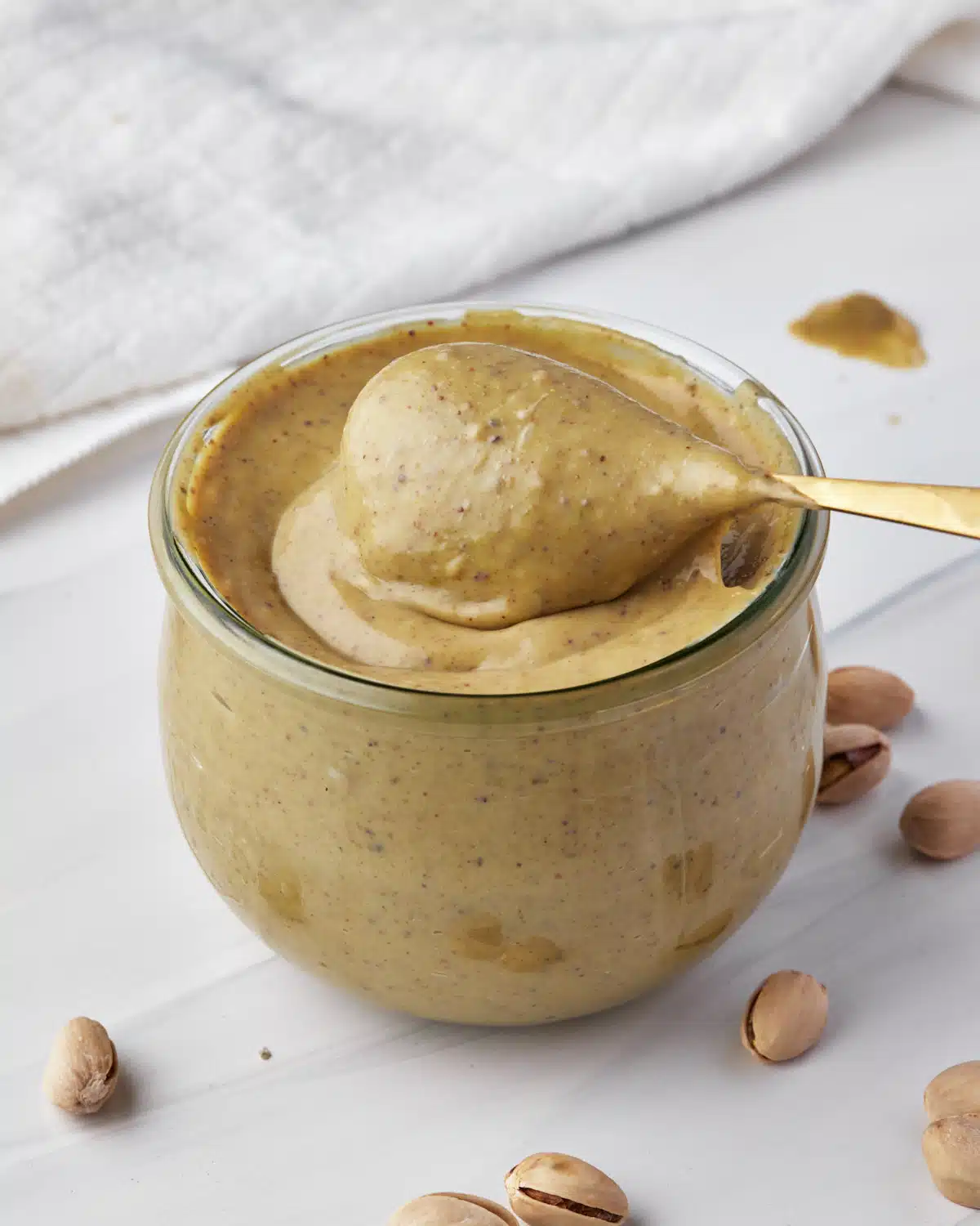 pistachio cream in a jar, with a spoonful being scooped out. 