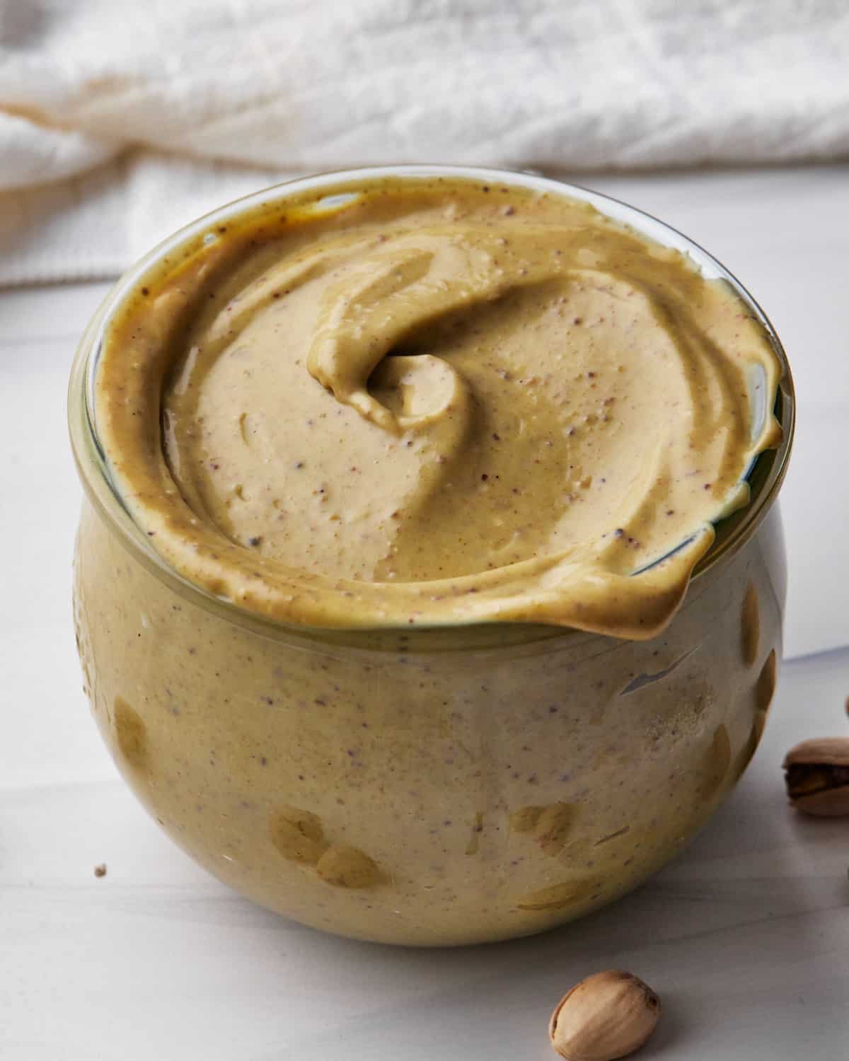 close up of pistachio cream in a glass jar. 