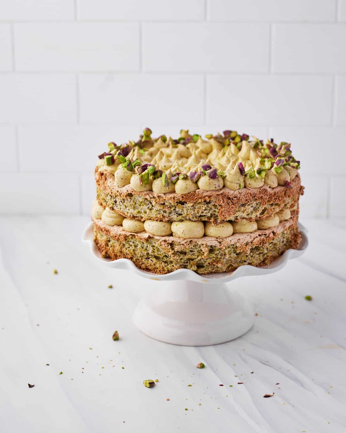 pistachio dacquoise cake decorated with pistachio french meringue buttercream and chopped pistachios. 