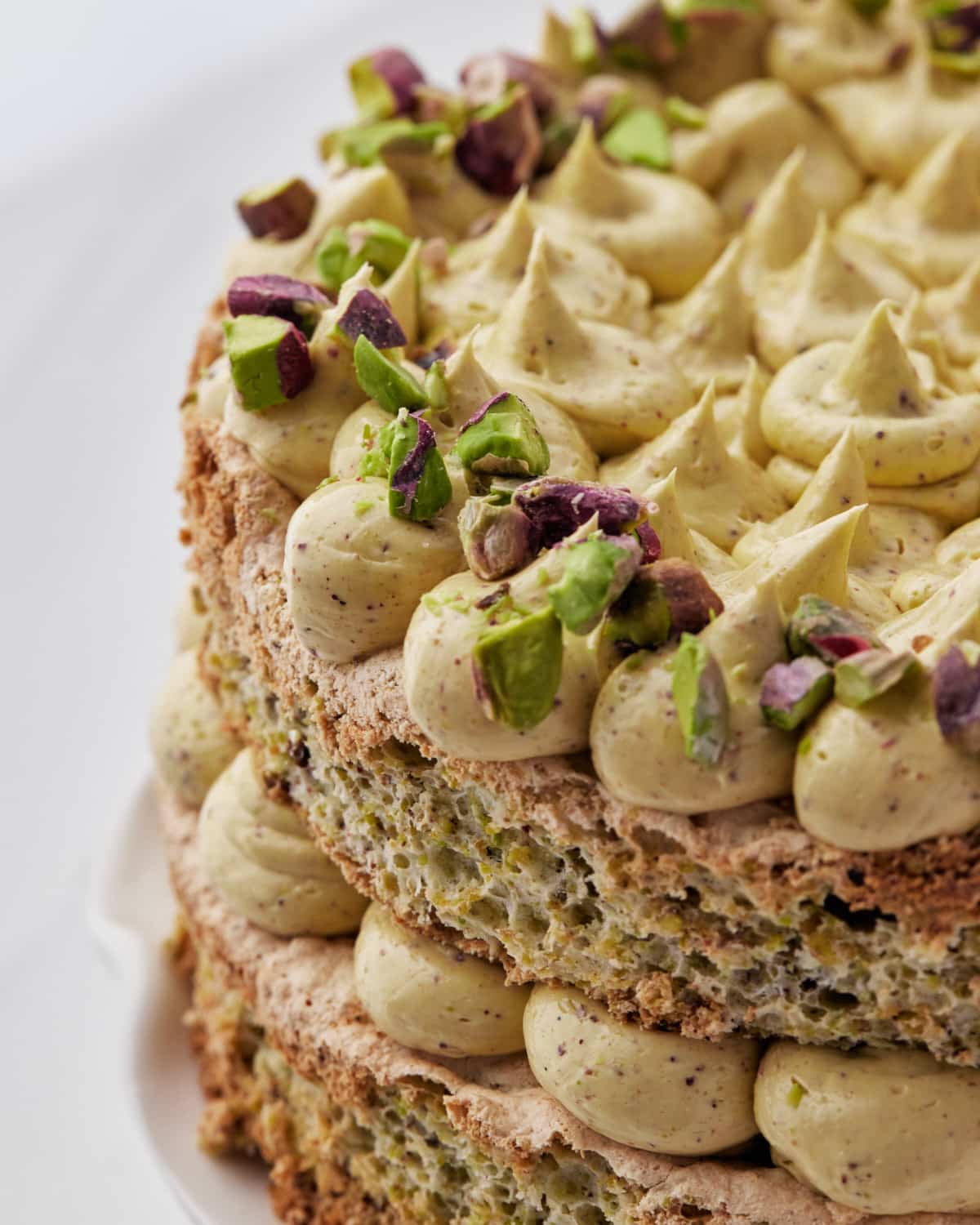 close up of pistachio dacquoise cake with pistachio french buttercream. 