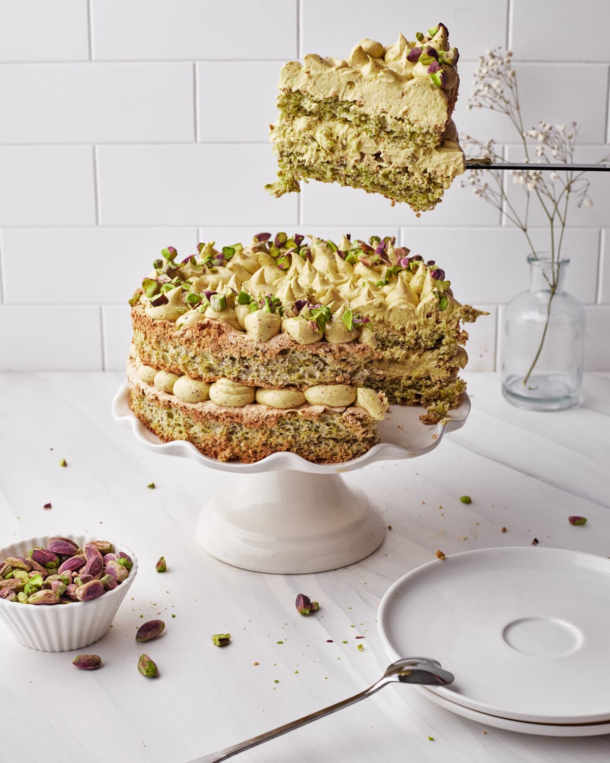 Slice of pistachio dacquoise being lifted out of the cake. 