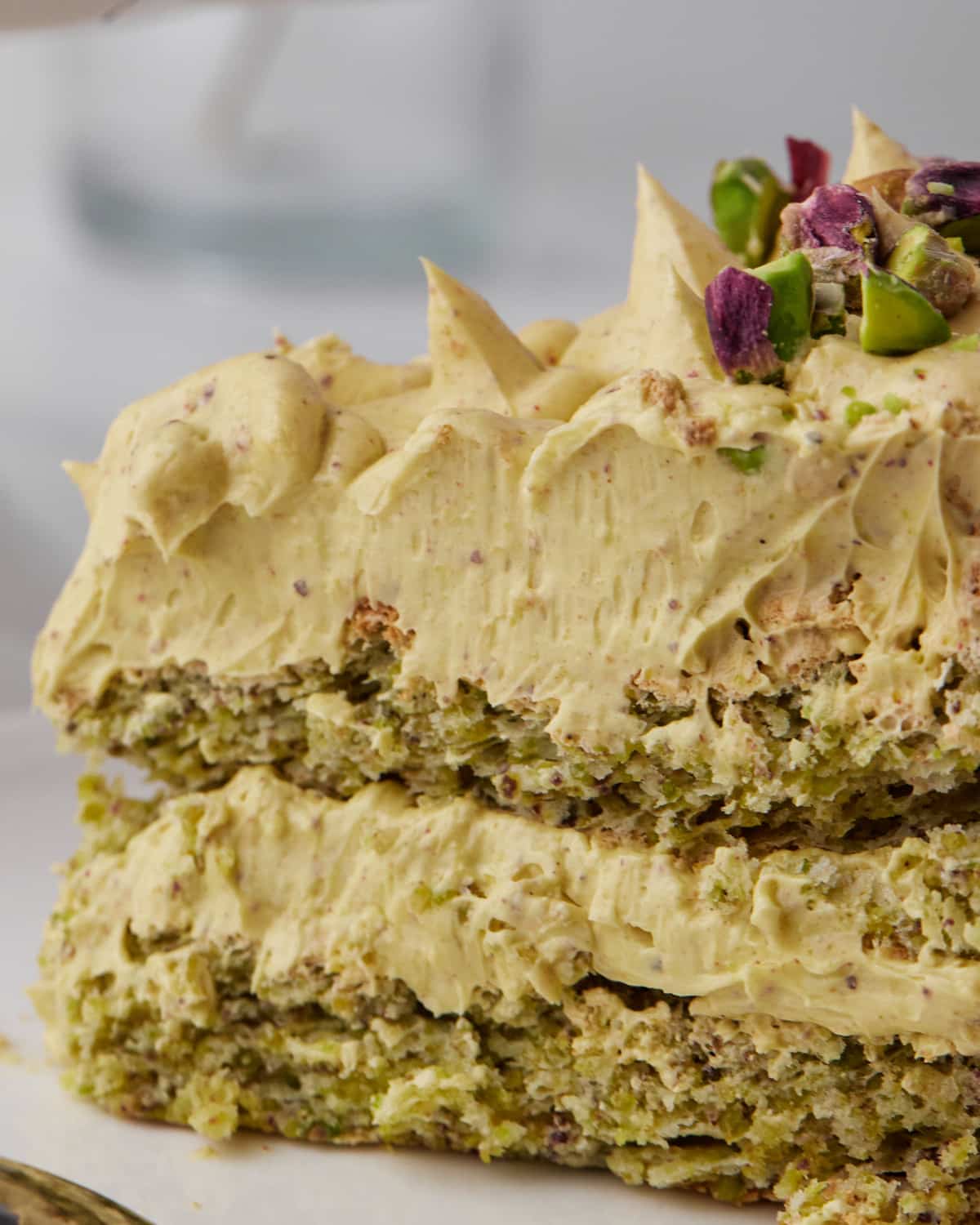 Close up of smooth french buttercream inside pistachio dacquoise. 