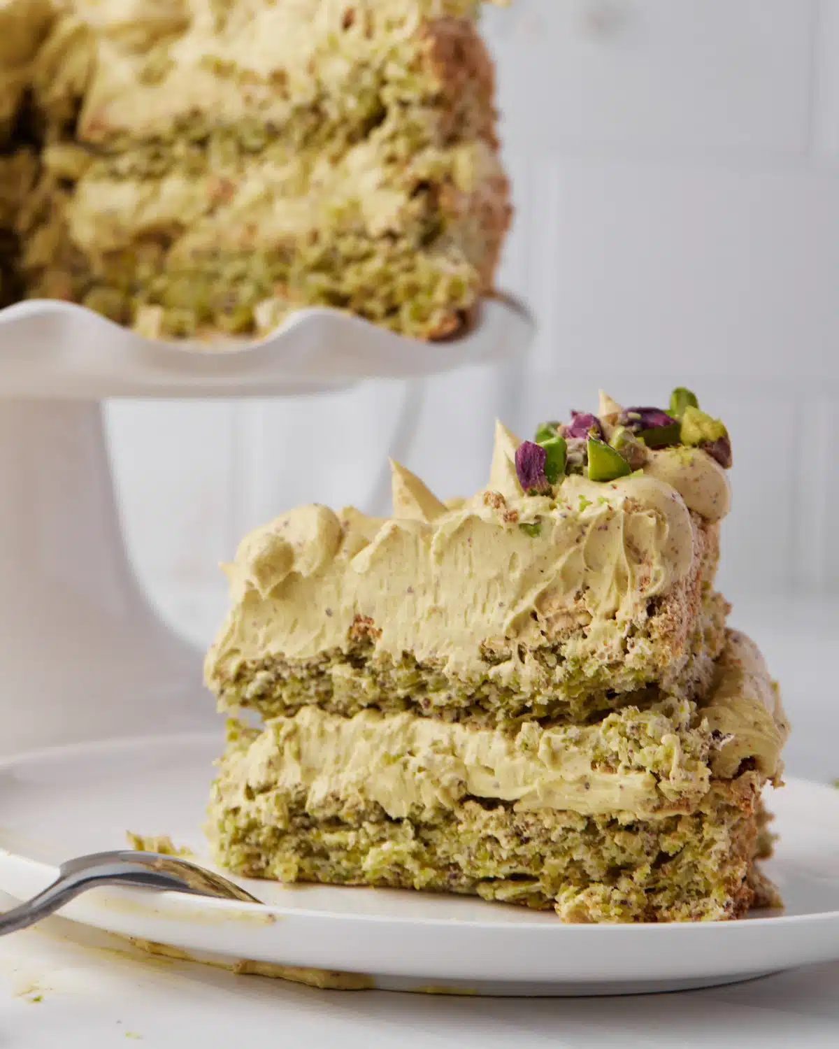 Slice of pistachio dacquoise decorated with pistachio French buttercream. 