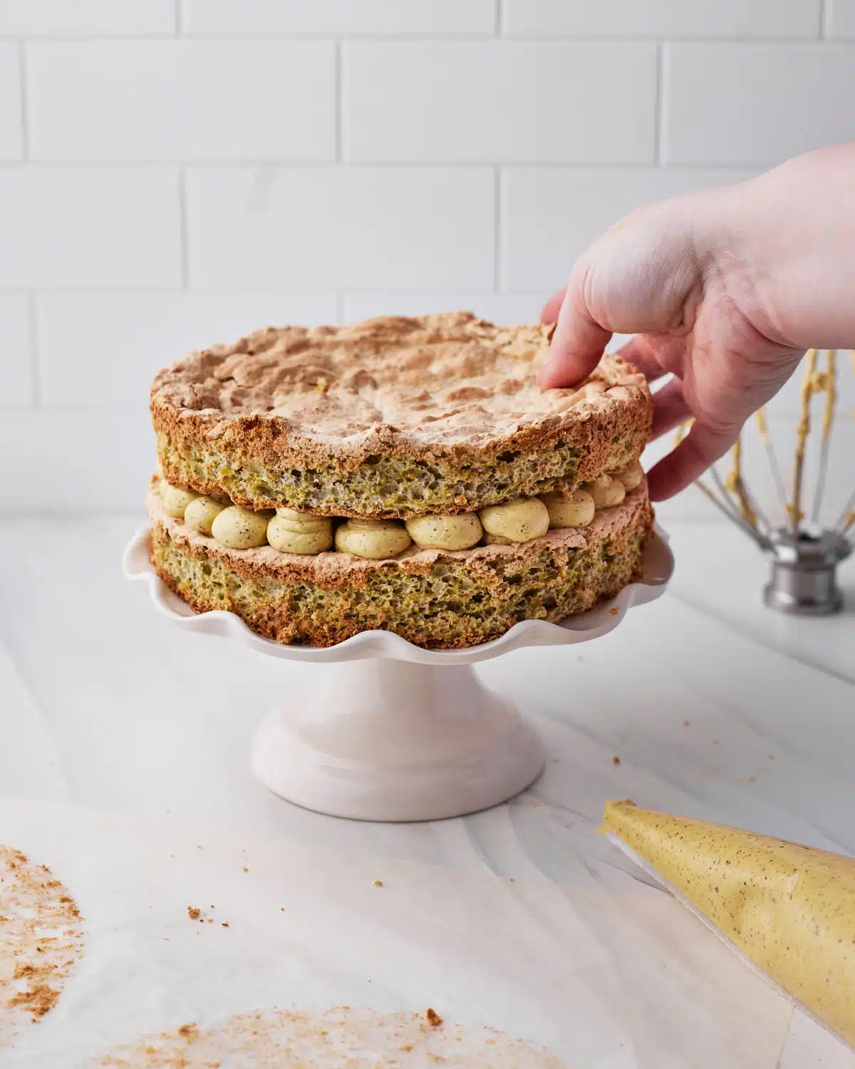 placing second layer of pistachio dacquoise on top of french buttercream.