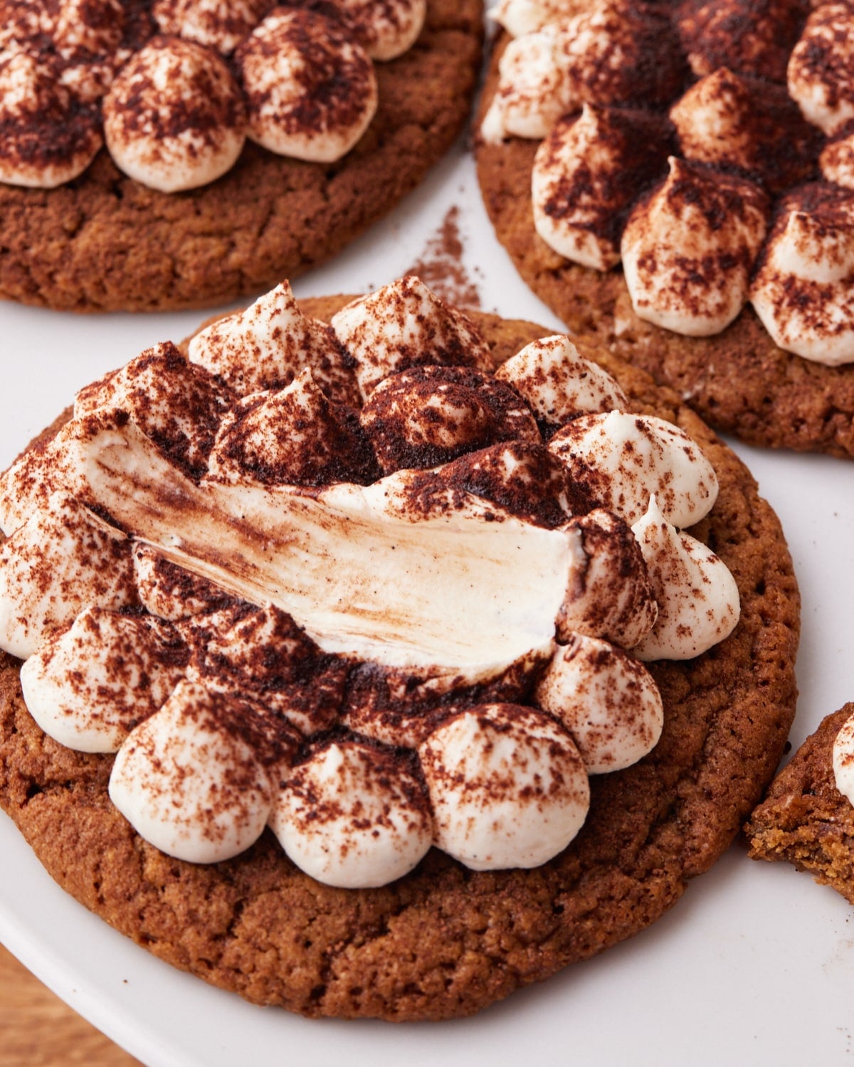 Tiramisu cookie with mascarpone cream piped on top in little blobs and a sprinkling of cocoa powder, with a scoop taken out to show the silky texture.