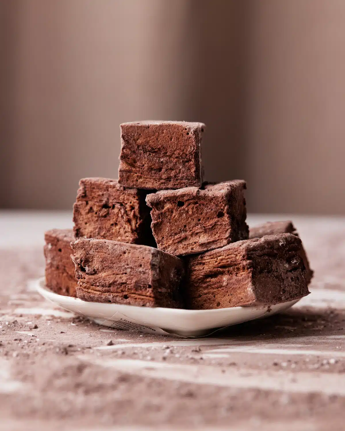 chocolate marshmallow squares in a pile on a small plate.