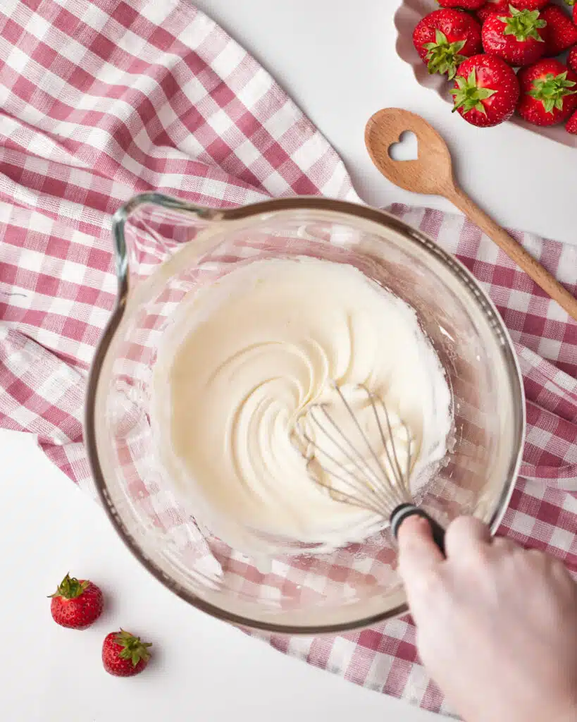 process shot for strawberry brownies, sugar and eggs in a large mixing bowl, being whisked together.
