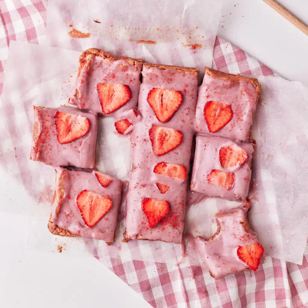strawberry brownies cut up into squares, decorated with strawberry ganache.