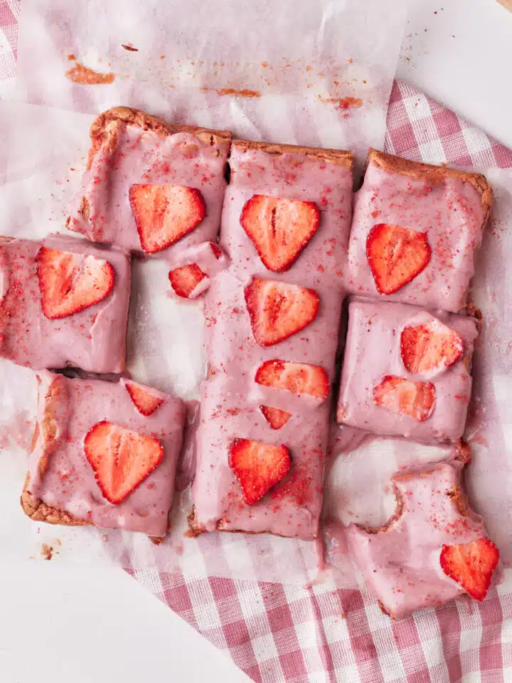 strawberry brownies cut up into squares, decorated with strawberry ganache.