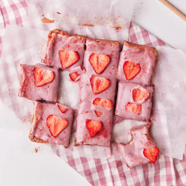 strawberry brownies cut up into squares, decorated with strawberry ganache.