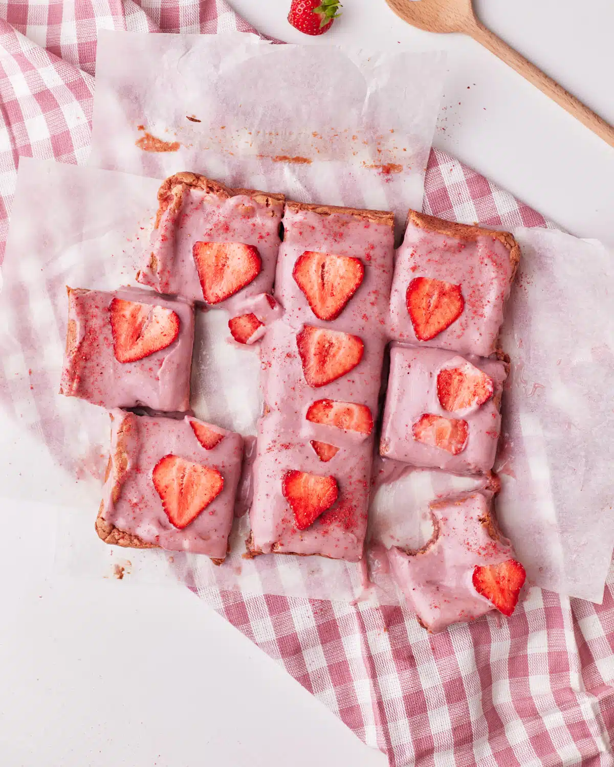 strawberry brownies with strawberry ganache cut into squares and topped with fresh strawberries. 