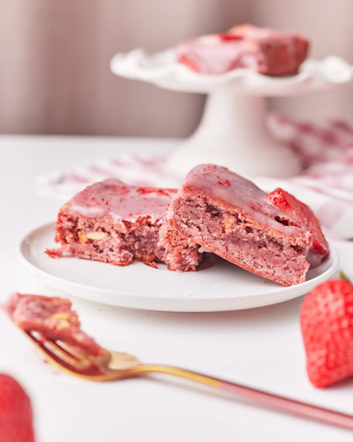 Two pink strawberry brownies on a plate, showing their lovely pink insides. 
