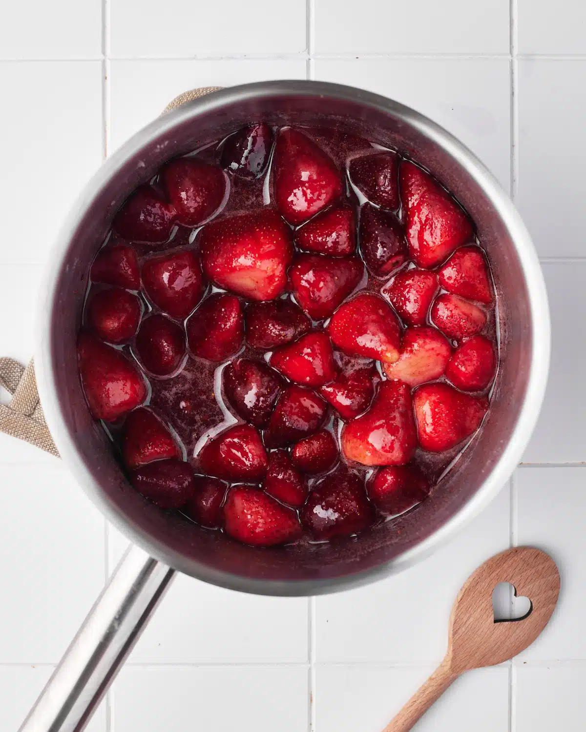 process shot of making strawberry puree, strawberries in a pan in sugar syrup. 