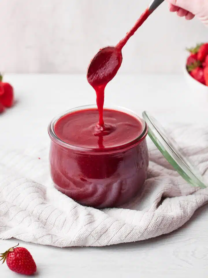 homemade strawberry coulis (strawberry puree) in a glass jar.