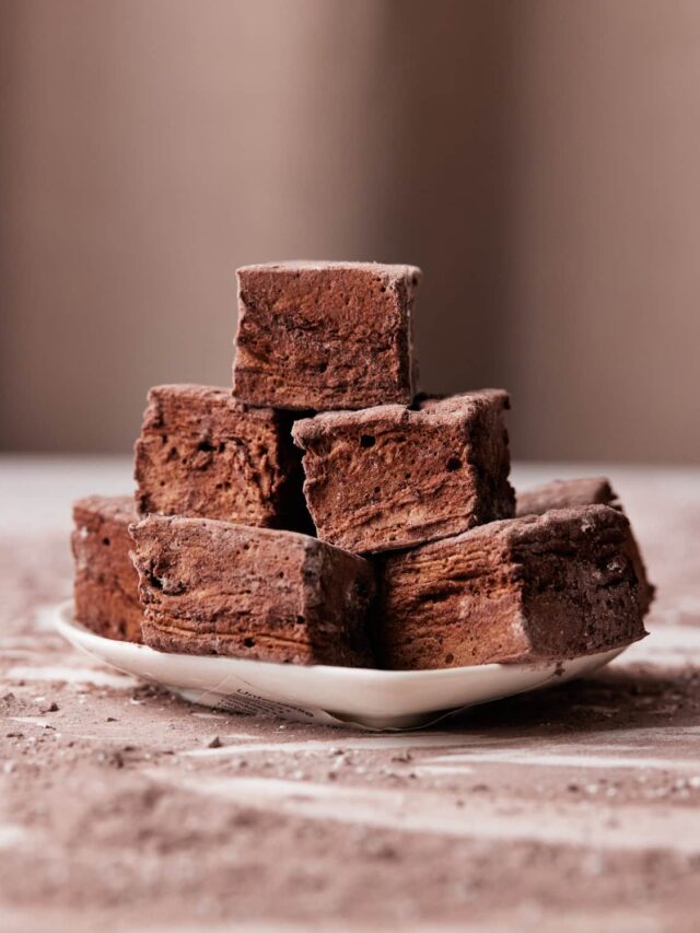 chocolate marshmallow squares in a pile on a small plate.