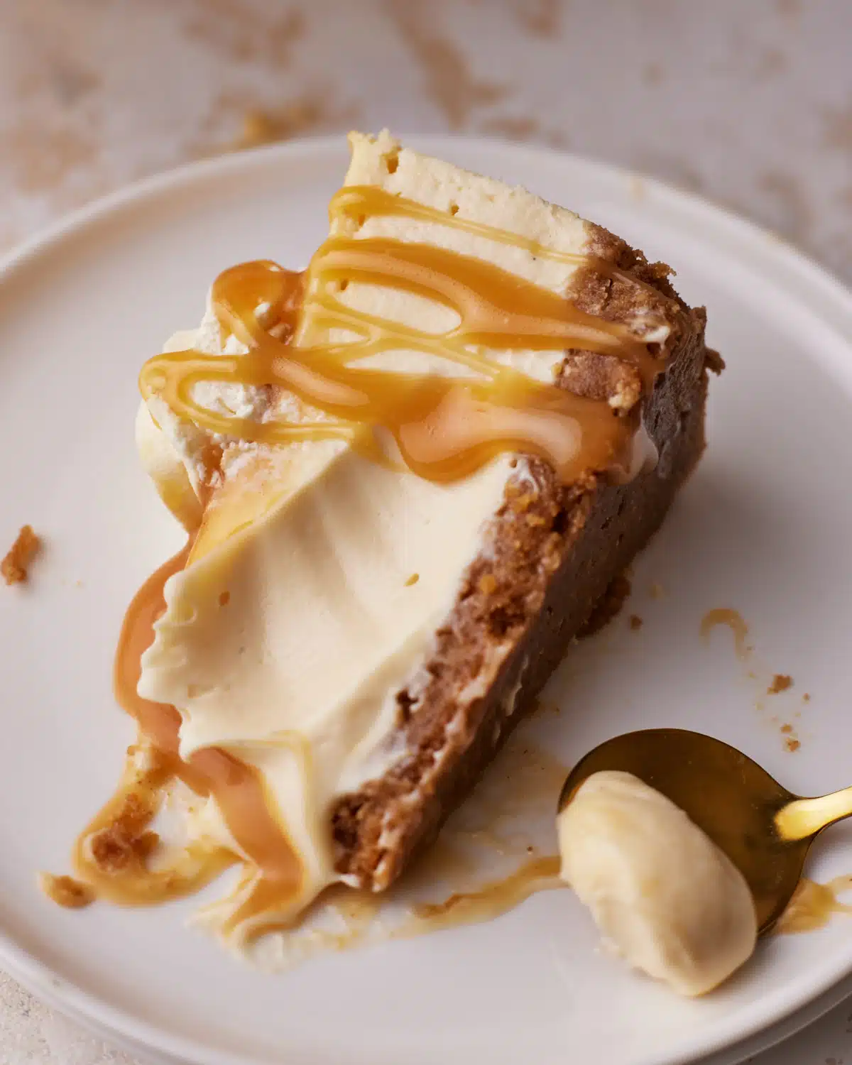 Slice of caramel cheesecake with a spoonful scooped out to show how creamy and smooth it is on the inside. 