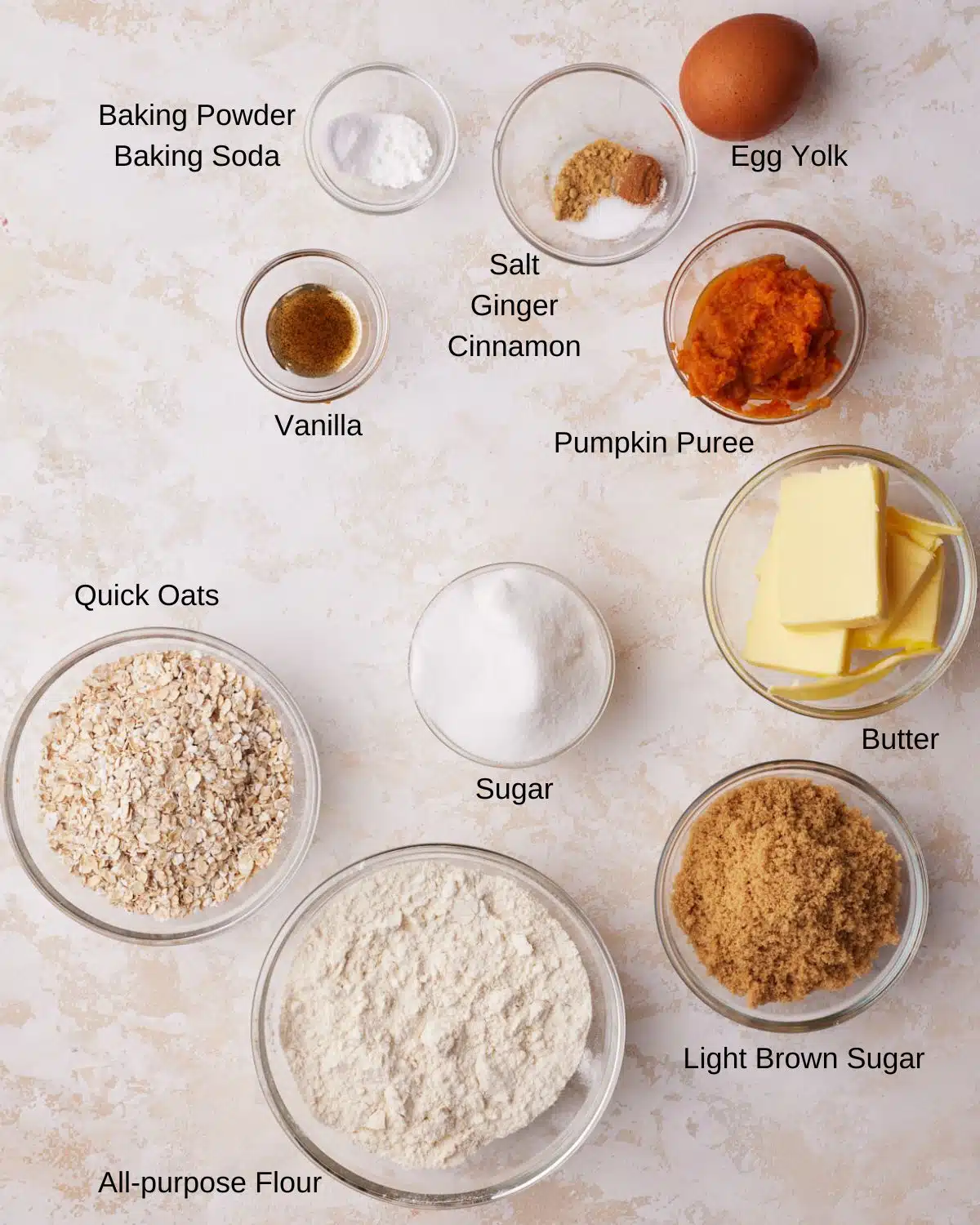 Ingredients shot to make pumpkin oatmeal cookies - flour, butter, sugar, light brown sugar, pumpkin puree, quick oats, cinnamon, ginger, vanilla.