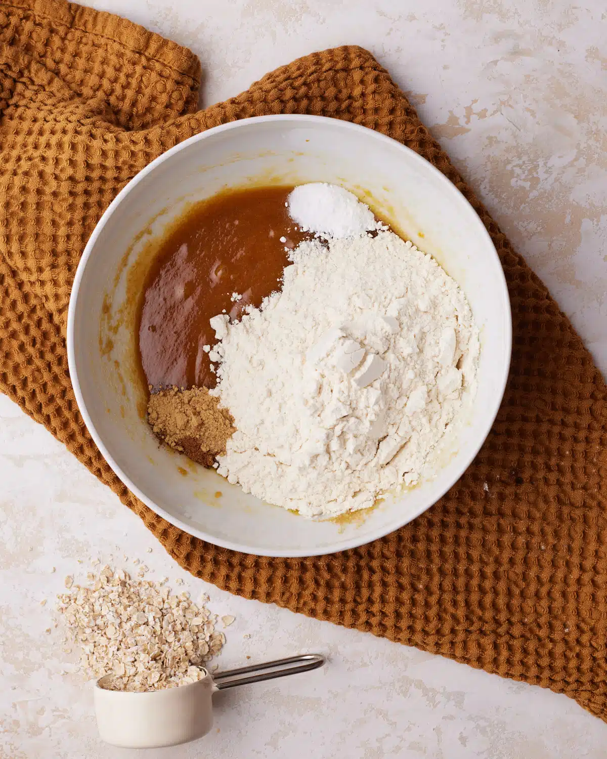 Dry ingredients being added to pumpkin oatmeal cookie dough.