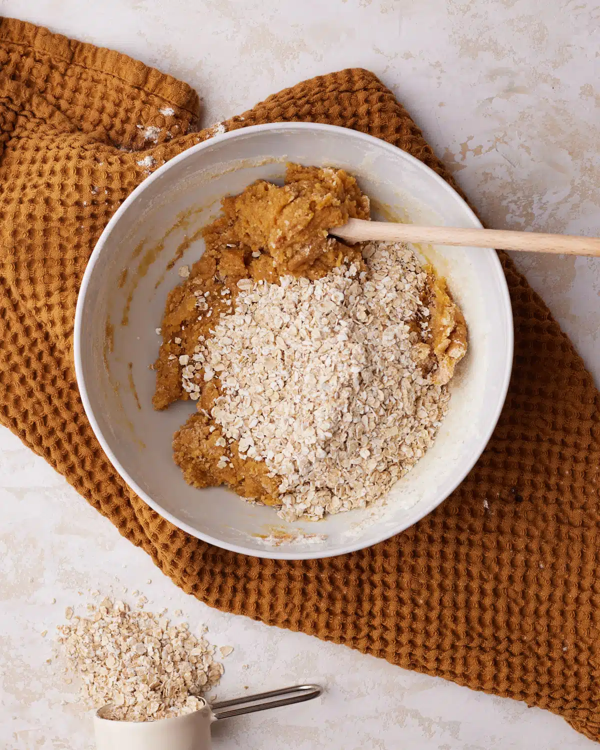 Oats being added to pumpkin oatmeal cookies.