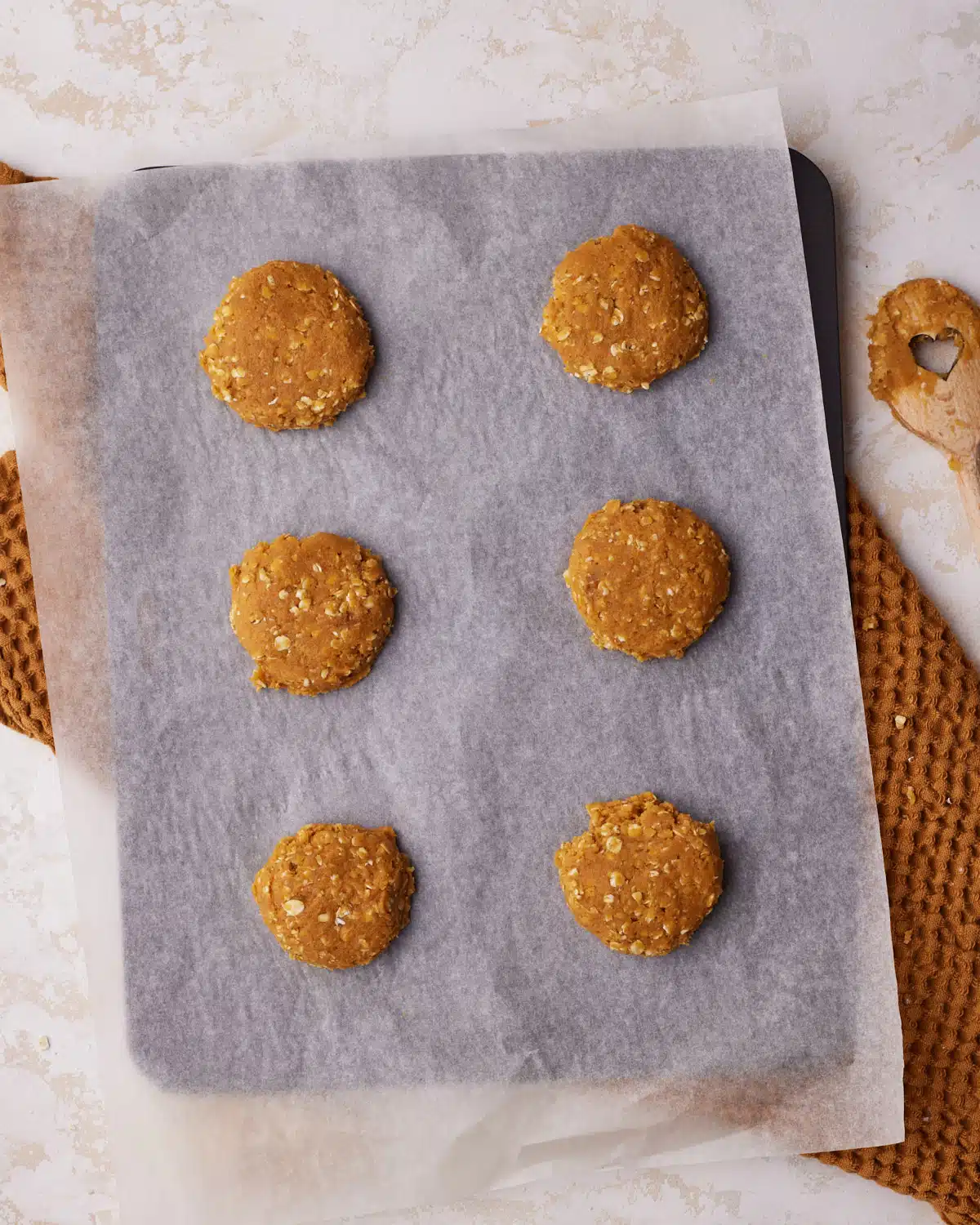 raw pumpkin oatmeal cookie dough on a baking sheet, ready to be baked. 