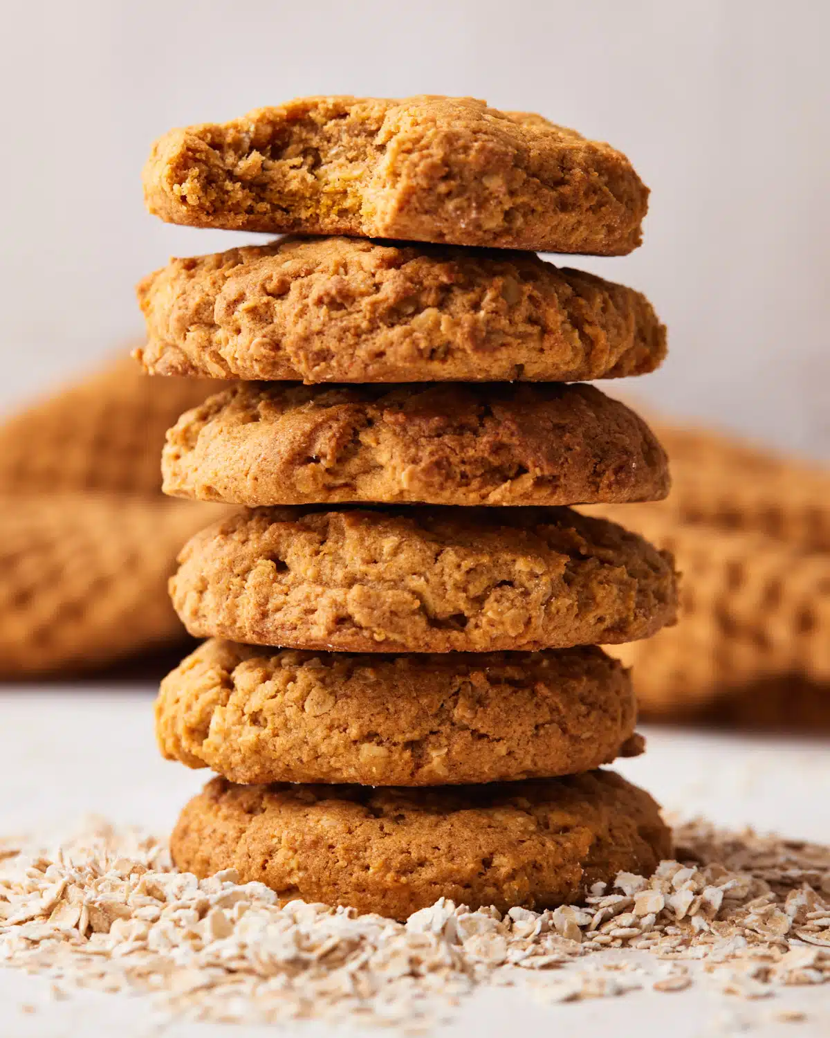 Stack of pumpkin oatmeal cookies, the top one has a bite taken out of it. 