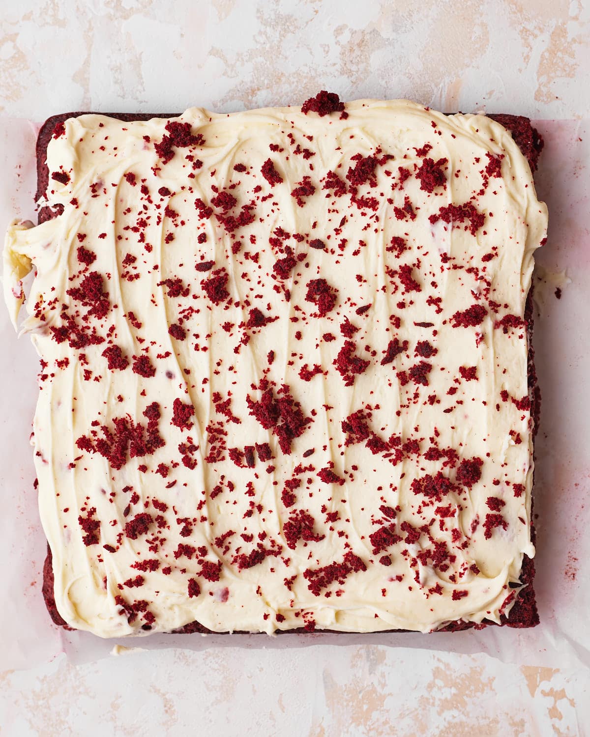 baked red velvet brownies with cream cheese frosting on top, ready to be sliced.