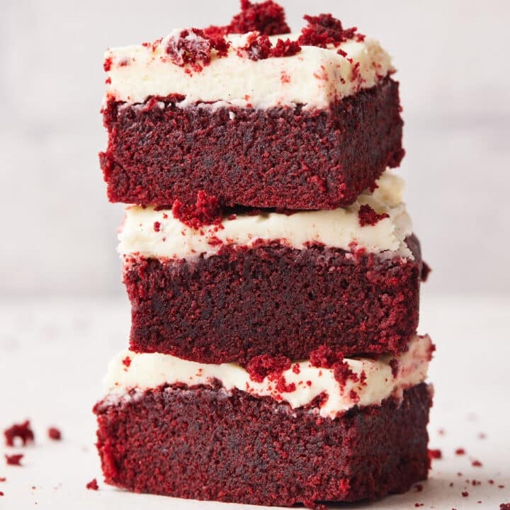three red velvet brownies stacked on top of each other with cream cheese frosting.