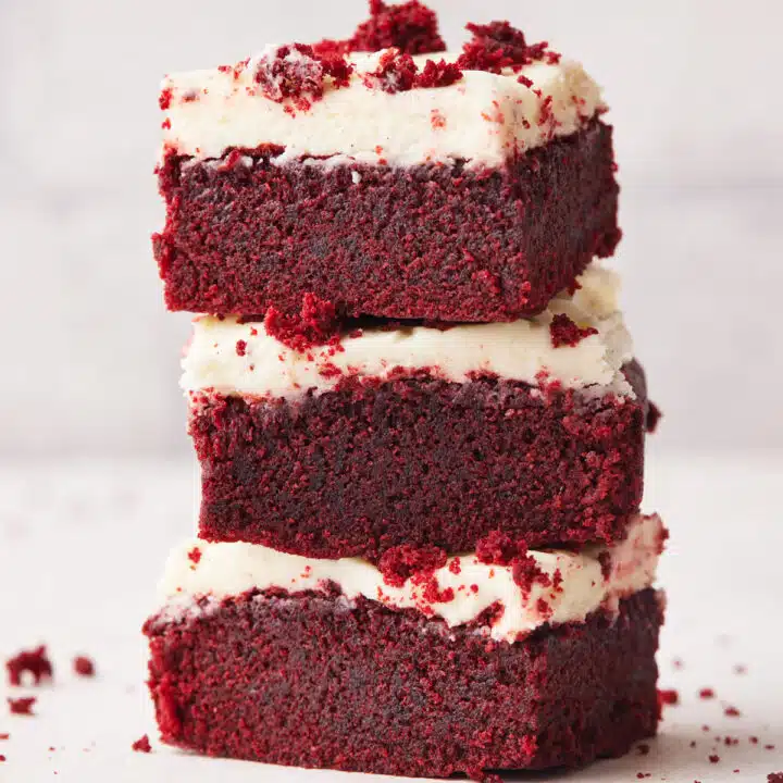 three red velvet brownies stacked on top of each other with cream cheese frosting.