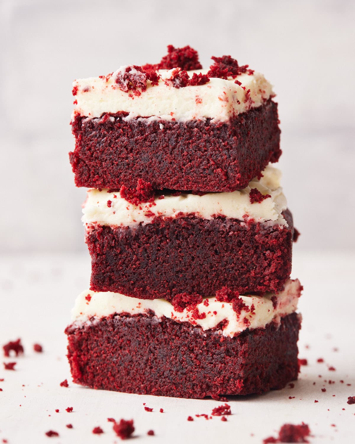 three red velvet brownies stacked on top of each other with cream cheese frosting.